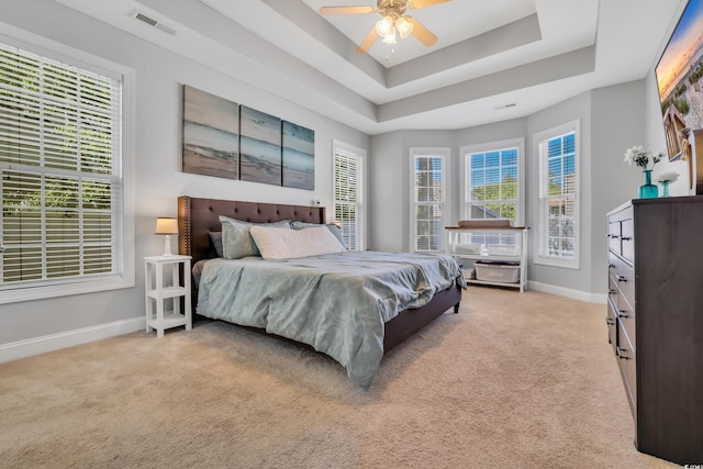 bedroom with visible vents, baseboards, ceiling fan, light colored carpet, and a raised ceiling