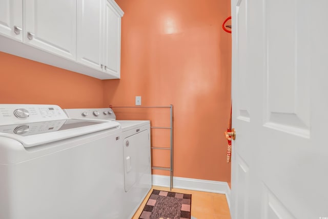 laundry room featuring cabinet space, baseboards, washing machine and dryer, and tile patterned flooring