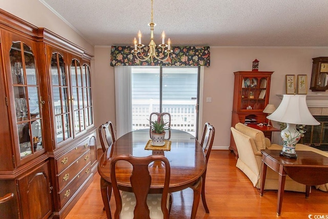 dining room featuring a notable chandelier, a textured ceiling, light wood finished floors, and a healthy amount of sunlight