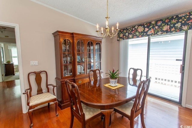 dining area featuring a healthy amount of sunlight, a chandelier, a textured ceiling, and light wood-type flooring