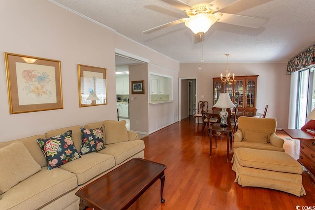 living room with ornamental molding, wood finished floors, a textured ceiling, and ceiling fan with notable chandelier