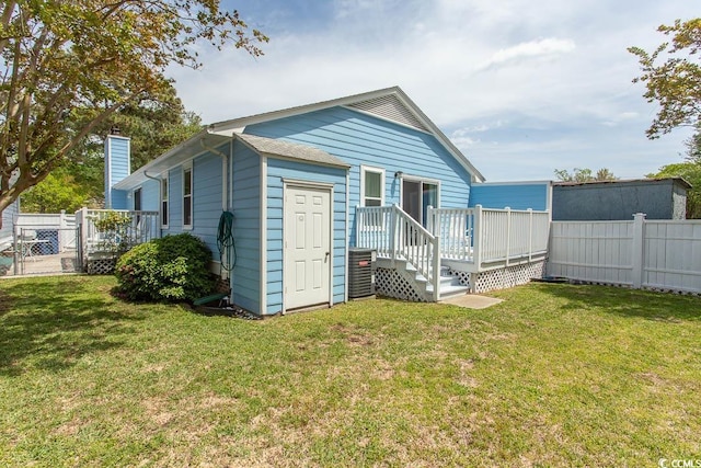 back of property with a wooden deck, a yard, a chimney, and fence