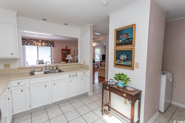 kitchen featuring white cabinets, light countertops, a sink, light tile patterned flooring, and a textured ceiling