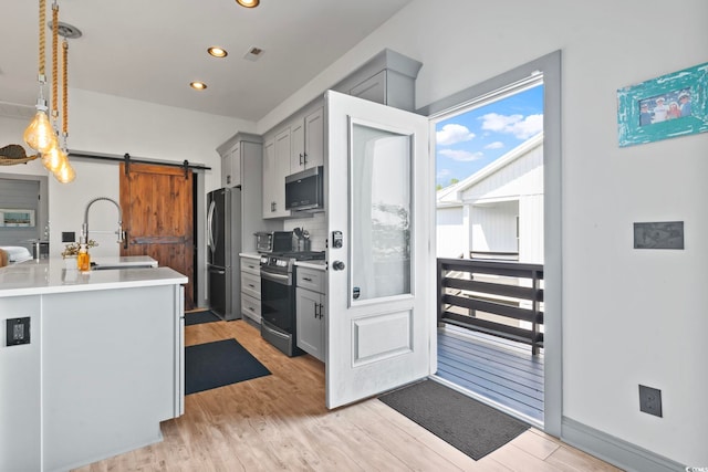 19 Red Skiff Ln Unit 15, Pawleys Island, SC 29585 - kitchen with appliances with stainless steel finishes, a barn door, gray cabinetry, light wood finished floors, and light countertops