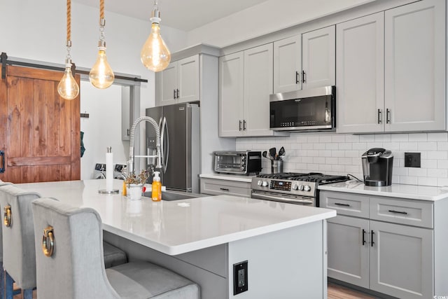 19 Red Skiff Ln Unit 15, Pawleys Island, SC 29585 - kitchen featuring appliances with stainless steel finishes, a barn door, gray cabinetry, and a breakfast bar