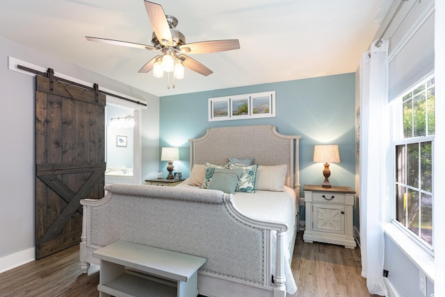 7011 Blade Beak Ln, Myrtle Beach, SC 29588 - bedroom with ensuite bath, a barn door, baseboards, and wood finished floors