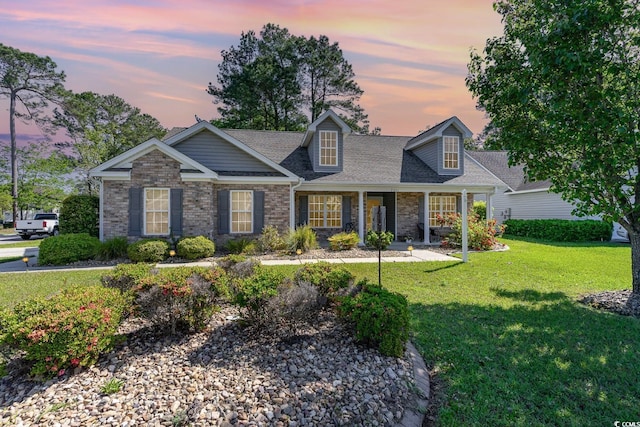 7011 Blade Beak Ln, Myrtle Beach, SC 29588 - view of front of home featuring a porch, a lawn, a shingled roof, and brick siding