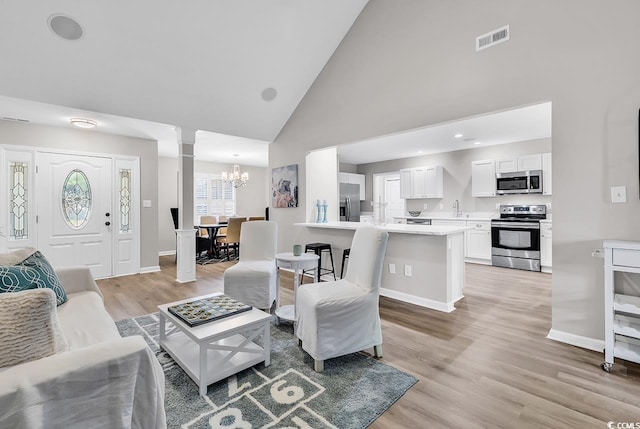 130 Ashton Cir, Myrtle Beach, SC 29588 - living area featuring light wood finished floors, visible vents, a notable chandelier, ornate columns, and high vaulted ceiling