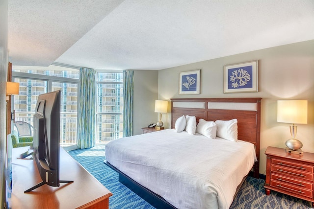 bedroom featuring floor to ceiling windows, access to exterior, and a textured ceiling