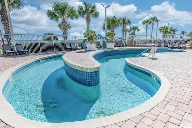 pool with a patio area and fence