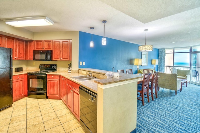kitchen with a sink, a peninsula, a textured ceiling, black appliances, and pendant lighting