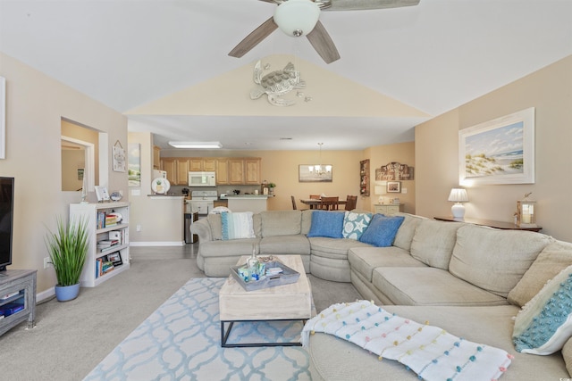 living room featuring vaulted ceiling, light colored carpet, ceiling fan with notable chandelier, and baseboards
