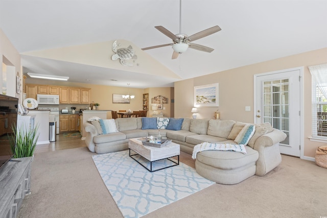 living area with light carpet, lofted ceiling, and ceiling fan with notable chandelier