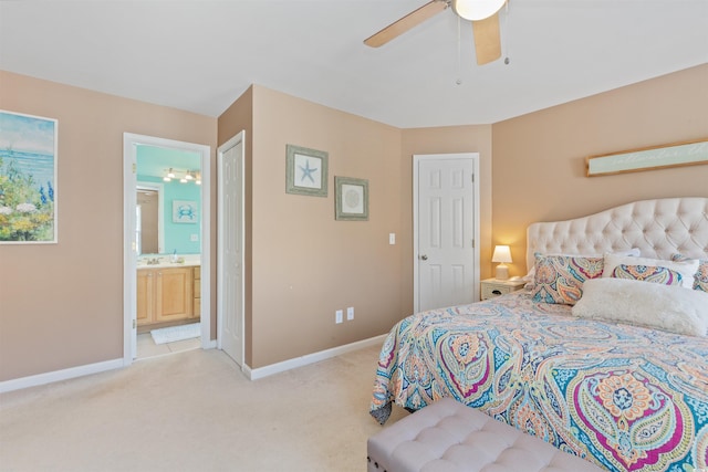 bedroom with ensuite bath, light carpet, baseboards, and a ceiling fan