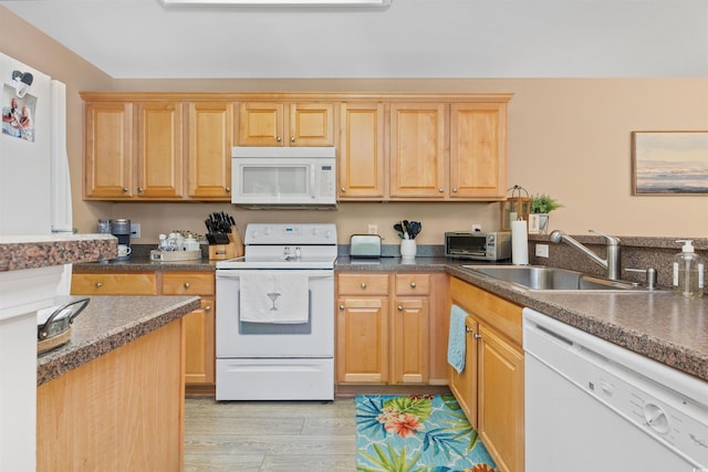 kitchen with a sink, white appliances, a toaster, dark countertops, and light wood-style floors