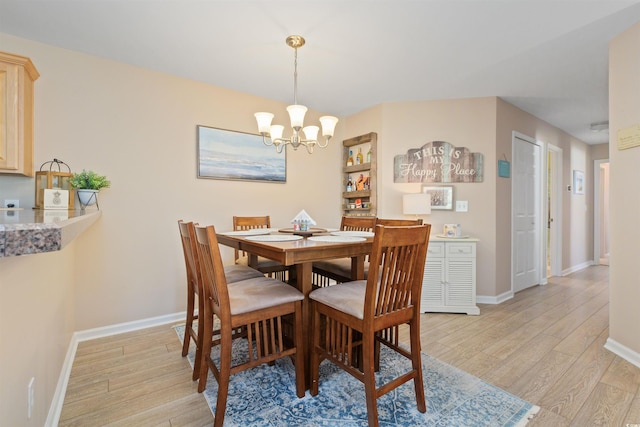 dining area with an inviting chandelier, light wood-style flooring, and baseboards