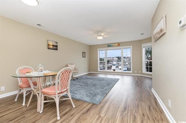 dining space with visible vents, baseboards, a ceiling fan, and wood finished floors
