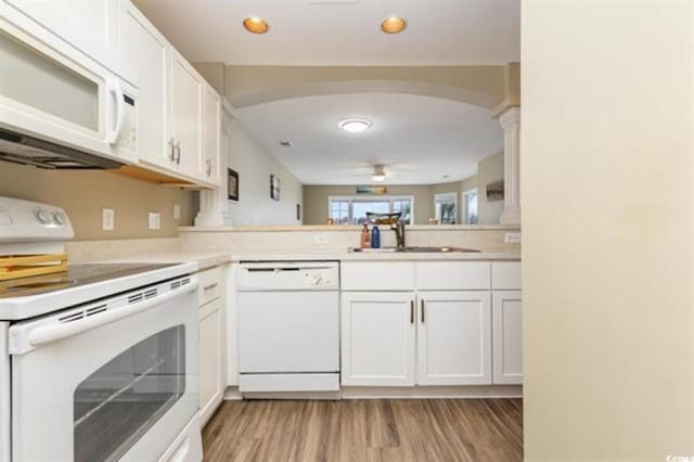 kitchen featuring white cabinets, light wood finished floors, a sink, white appliances, and ceiling fan