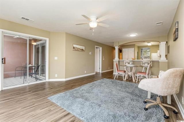 interior space featuring wood finished floors, visible vents, ceiling fan, and decorative columns
