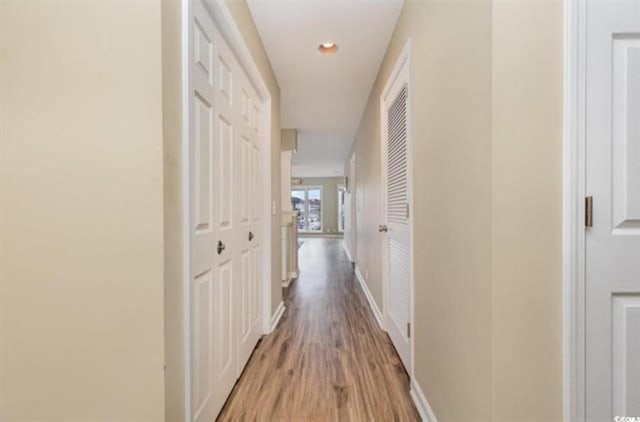 corridor featuring recessed lighting, light wood-type flooring, and baseboards