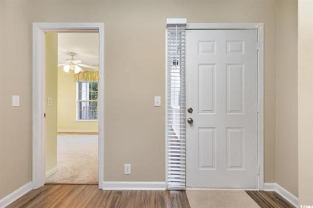 foyer entrance with baseboards, a ceiling fan, and wood finished floors