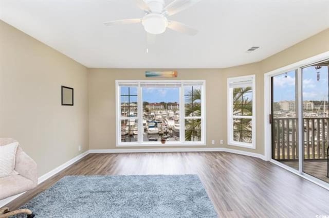 unfurnished room featuring baseboards, wood finished floors, visible vents, and a wealth of natural light