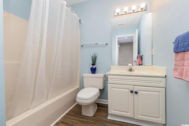 bathroom featuring wood finished floors, shower / bath combo with shower curtain, toilet, and vanity