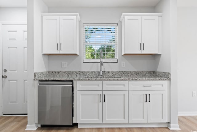 bar featuring light wood-style flooring, a sink, and stainless steel dishwasher