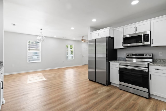 kitchen with light wood finished floors, stainless steel appliances, white cabinets, and ceiling fan with notable chandelier