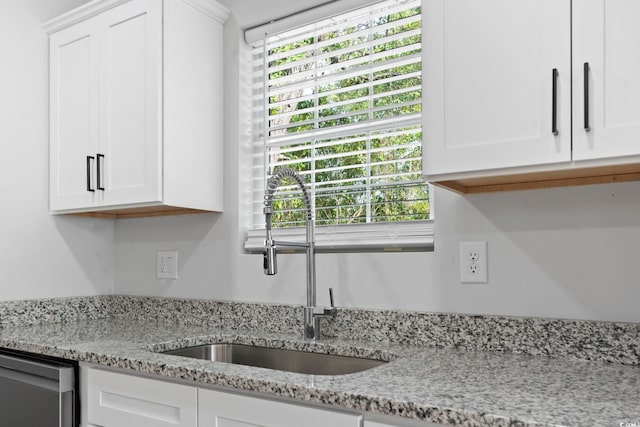 room details featuring light stone countertops, white cabinets, a sink, and dishwasher