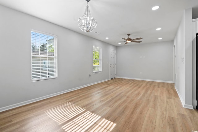spare room with ceiling fan with notable chandelier, a healthy amount of sunlight, and recessed lighting