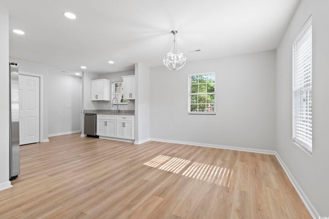 unfurnished living room with an inviting chandelier, a sink, baseboards, light wood-style floors, and recessed lighting