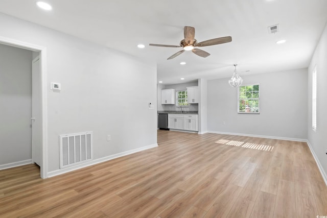 unfurnished living room with visible vents, light wood-style flooring, ceiling fan with notable chandelier, and recessed lighting