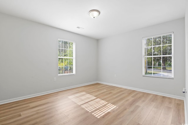 spare room with baseboards, visible vents, and light wood-type flooring