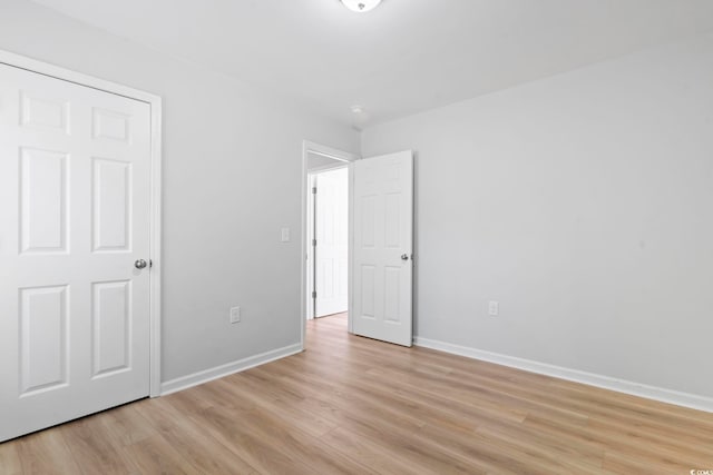 unfurnished bedroom with baseboards and light wood-type flooring