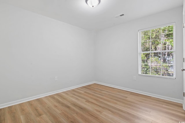 spare room featuring a healthy amount of sunlight, baseboards, visible vents, and light wood-style floors