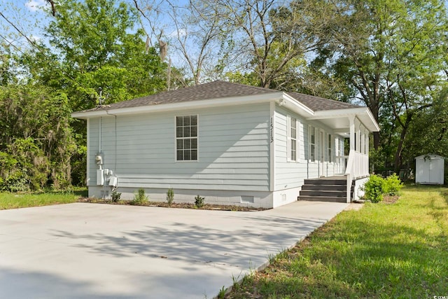 view of side of home with a lawn, crawl space, and roof with shingles