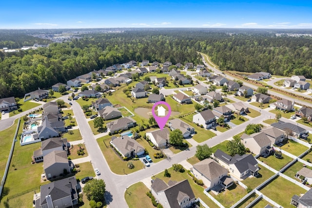 aerial view of property and surrounding area with a heavily wooded area and nearby suburban area