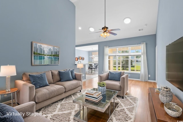 living area featuring a ceiling fan, wood finished floors, high vaulted ceiling, and baseboards