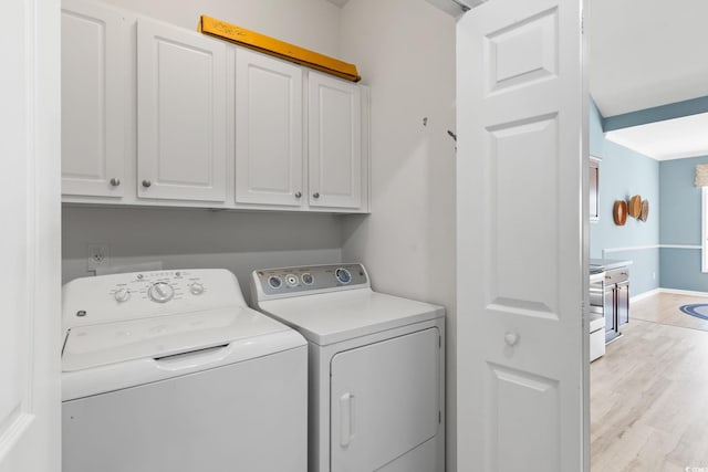 clothes washing area featuring cabinet space, washer and clothes dryer, light wood-style flooring, and baseboards