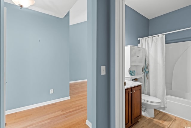 bathroom with wood finished floors, toilet, vanity, shower / bath combo with shower curtain, and baseboards