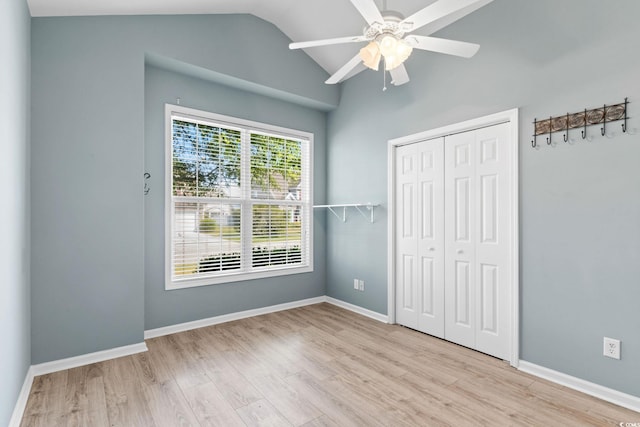 unfurnished bedroom with wood finished floors, lofted ceiling, a closet, baseboards, and a ceiling fan
