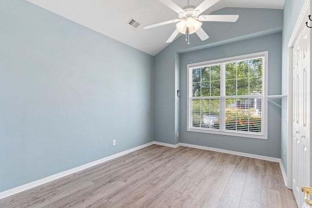 spare room featuring lofted ceiling, a ceiling fan, light wood-style flooring, and baseboards