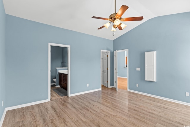 unfurnished bedroom with lofted ceiling, wood finished floors, connected bathroom, and baseboards