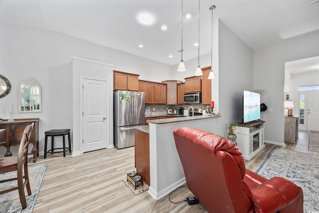 1208 Camlet Ln, Little River, SC 29566 - kitchen with stainless steel appliances, a peninsula, brown cabinets, light wood-type flooring, and tasteful backsplash