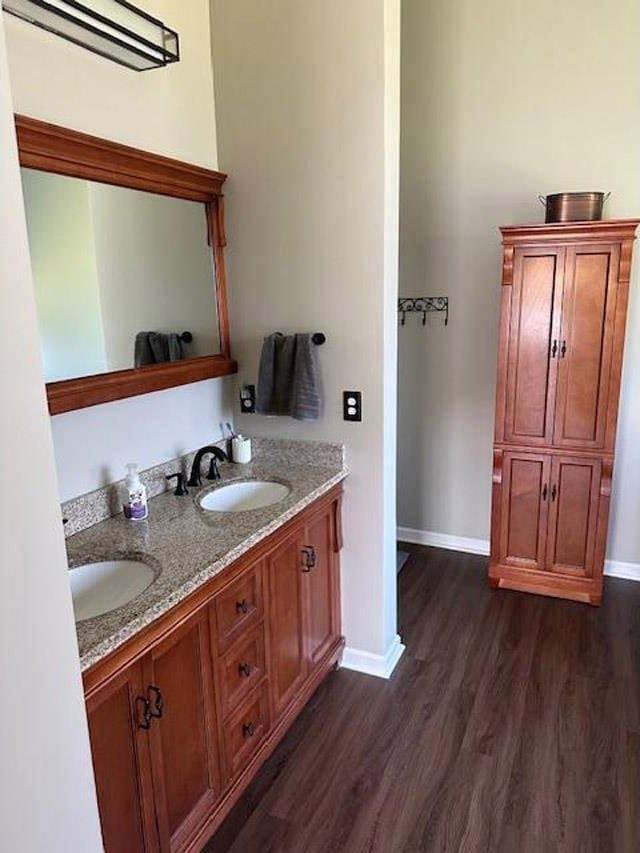 bathroom with baseboards, wood finished floors, and a sink