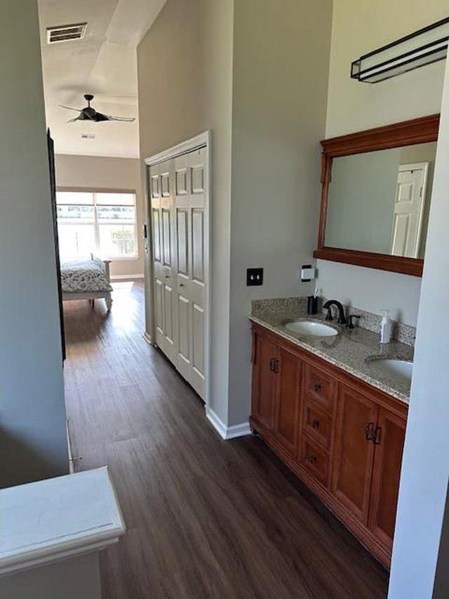bathroom featuring wood finished floors, visible vents, a sink, baseboards, and ceiling fan