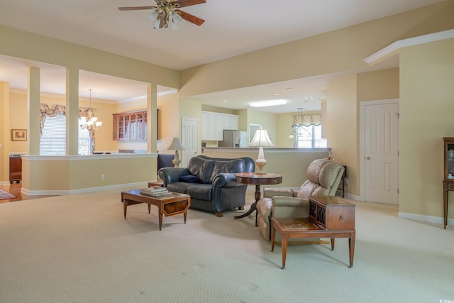 living room with baseboards, light carpet, and ceiling fan with notable chandelier