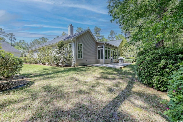 back of property with a yard, a patio area, and a chimney