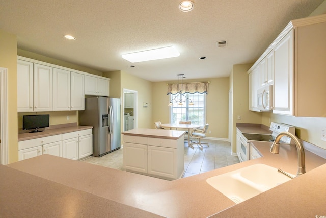 kitchen featuring white cabinets, visible vents, a sink, white appliances, and a textured ceiling